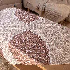 Square table cover with Arabic calligraphy from the 'أثر' collection in mocha tones, ideal for Ramadan decor.