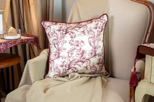 Burgundy patterned cushion cover styled on a sofa with matching decor.