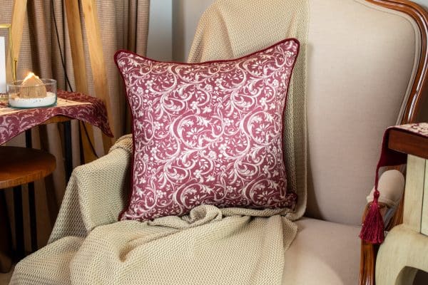 Burgundy patterned cushion cover styled on a sofa with matching decor.