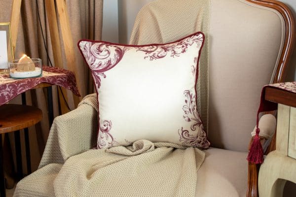 Burgundy patterned cushion cover styled on a sofa with matching decor.