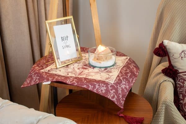 Burgundy side table cloth styled with matching decor accents and a small vase.