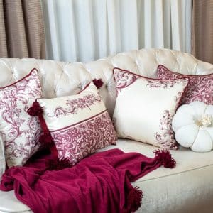 Burgundy patterned cushion cover styled on a sofa with matching decor.