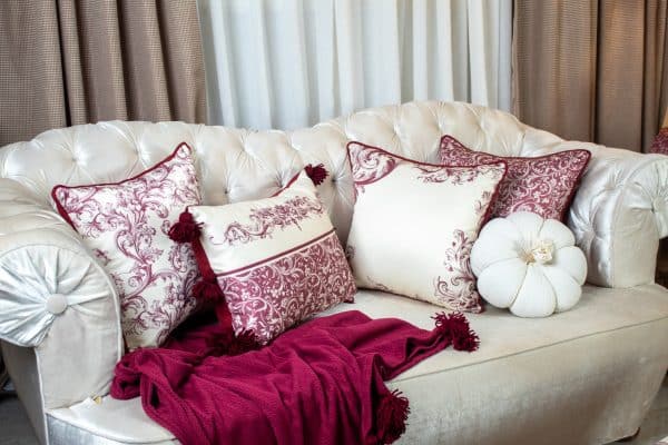 Burgundy patterned cushion cover styled on a sofa with matching decor.