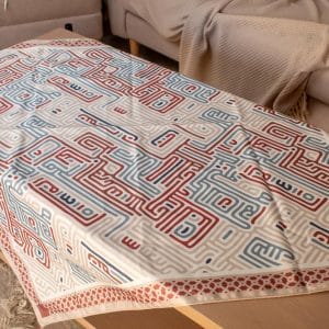 Square table cover with Kufic-inspired patterns from the 'كوفي' collection, ideal for Ramadan decor.