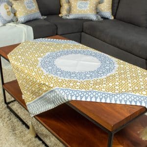 Square table cover with mustard and grey minaret motifs from the 'مآذن' collection.